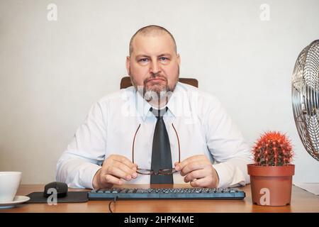 L'homme décrit comiquement le travail d'un homme d'affaires. Il montre son mécontentement sur son visage et sa posture. Banque D'Images