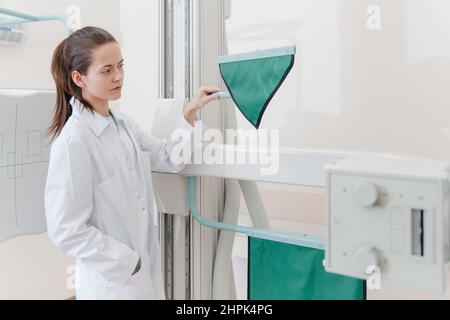 Salle de radiologie de l'hôpital. Appareil à rayons X pour la radiographie. Médecin radiologue en casaque en ajustant la machine à rayons X pour la radiographie. Équipement médical Banque D'Images