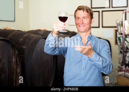 Homme goûtant du vin avant de l'acheter dans la cave de vinification Banque D'Images