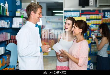 portrait de l'homme en manteau blanc donnant des conseils aux clients en pharmacie Banque D'Images