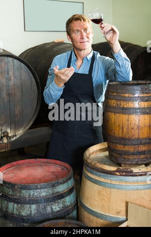 viticulteur tenant un verre de vin dans une cave. Banque D'Images