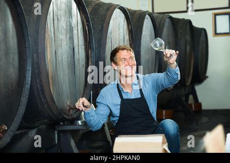 viticulteur tenant un verre de vin dans une cave. Banque D'Images