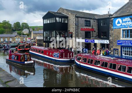 Voyage touristique en eau (auto-drive Red location bateau, hommes femmes file d'attente, bateaux amarrés, amarres) - pittoresque canal Leeds-Liverpool, Yorkshire, Angleterre Royaume-Uni Banque D'Images