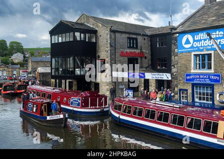 Voyage touristique en eau (auto-drive Red location bateau, hommes femmes file d'attente, bateaux amarrés, amarres) - pittoresque canal Leeds-Liverpool, Yorkshire, Angleterre Royaume-Uni Banque D'Images