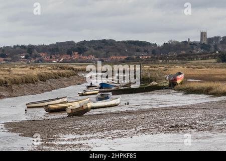 Bateaux et dinghies attendant la marée le jour terne à marée basse à Morston Creek, en hiver, dans le nord de Norfolk Banque D'Images