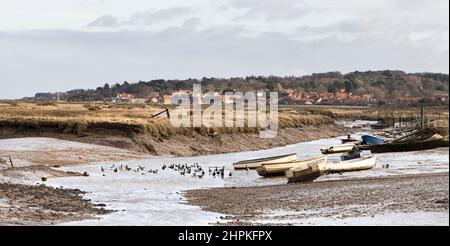 Bateaux et dinghies attendant la marée le jour terne à marée basse à Morston Creek, en hiver, dans le nord de Norfolk Banque D'Images