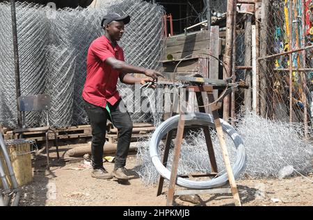 (220222) -- HARARE, 22 février 2022 (Xinhua) -- Un homme fait des clôtures à Magaba, Mbare, Harare, Zimbabwe, 8 février, 2022. Pour de nombreux visiteurs, Mbare, qui est l'un des établissements à faible revenu de Harare, semble être un canton chaotique et crasseux. Les rues poussiéreuses de la région, les immeubles d'appartements délabrés et ses marchés de bord de route bondés ne font pas le règlement une faveur. Malgré tout le chaos qui caractérise Mbare, un examen plus en détail révèle que parmi tout ce chaos se trouvent des citoyens industrieux qui tentent de faire de leur mieux pour vivre dans un environnement économique difficile. POUR ALLER AVEC « caractéristique : remorquage historique Banque D'Images