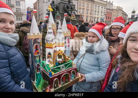 Les filles d'école portant la scène de la nativité de Cracovie Szopka qu'elles ont faite, pour exposition pendant le concours annuel en décembre, au monument Adam Mickiewicz, place du marché principal, Cracovie, Pologne Banque D'Images