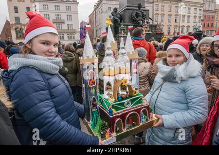 Les filles d'école portant la scène de la nativité de Cracovie Szopka qu'elles ont faite, pour exposition pendant le concours annuel en décembre, au monument Adam Mickiewicz, place du marché principal, Cracovie, Pologne Banque D'Images