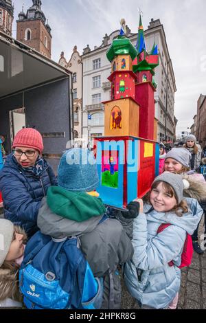 Écoliers, enseignant portant la scène de la nativité de Cracovie Szopka qu'ils ont faite, pour exposition pendant le concours annuel en décembre, au monument Adam Mickiewicz, place du marché principal, Cracovie, Pologne Banque D'Images