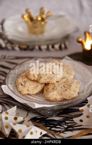 Petits gâteaux de noël faits main meringue et choco servis sur une assiette de verre, une serviette blanche et un plateau en pierre, dans une table de fête avec des décorations et des bougies Banque D'Images