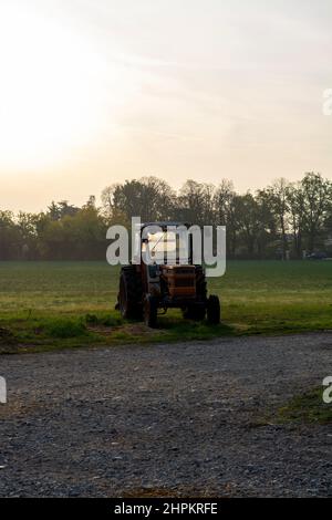 Vieux tracteurs d'époque dans les rayons du soleil tôt le matin sur la fromagerie dans le nord de l'Italie Banque D'Images