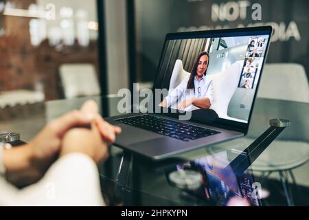 Femme d'affaires anonyme assistant à une réunion virtuelle dans un lieu de travail moderne. Femme d'affaires méconnue qui utilise un ordinateur portable pour passer un appel vidéo à son secteur d'activité Banque D'Images