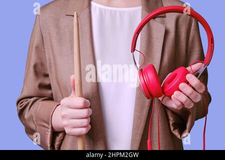 Femme enseignante tenant des écouteurs rouges dans ses mains sur fond bleu, gros plan Banque D'Images