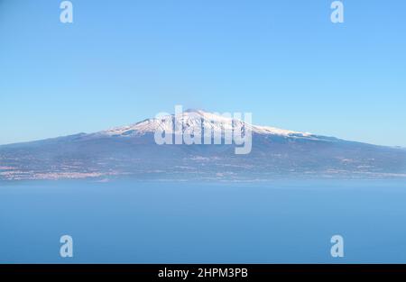 Vue aérienne de l'Etna, un volcan actif en Sicile, avec un pic de montagne enneigé et la ville de Catane, depuis la mer Méditerranée Banque D'Images