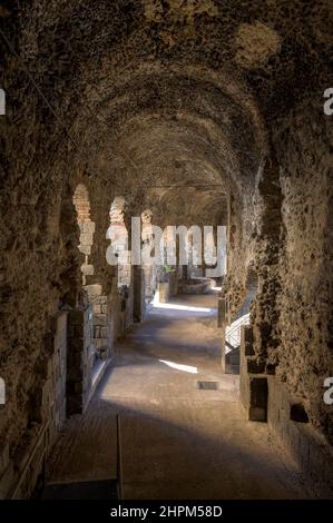 Galerie souterraine périphérique ou vomatorium fait de pierres volcaniques, courrant autour de l'ancien amphithéâtre romain de Catane en Sicile, Italie Banque D'Images