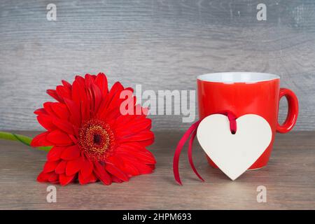 grande fleur rouge avec tasse à café et coeur sur fond rustique en bois Banque D'Images