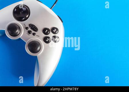 Photo de la manette de jeu classique filaire moderne couleur argent posée sur fond bleu. Banque D'Images