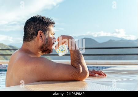 Homme buvant dans une piscine bénéficiant de la vue sur la ville de Chanchamayo situé dans le département de Junin au Pérou Banque D'Images