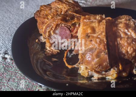 rouleaux de poulet farcis rôtis placés sur une assiette noire, espace de copie restant. Banque D'Images