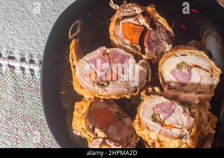 rouleaux de poulet farcis rôtis placés sur une assiette noire, espace de copie restant. Banque D'Images