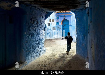 Vue d'une allée couverte avec un garçon sur le côté droit à Chefchaouen, Maroc Banque D'Images