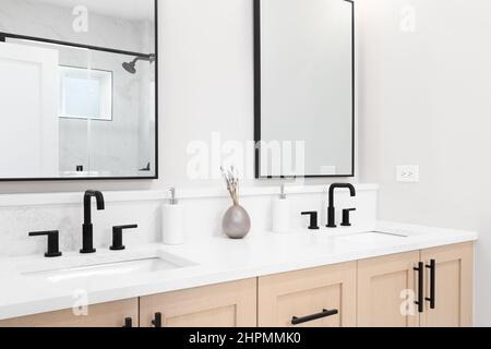 Salle de bains moderne avec meuble-lavabo en bois, robinets noirs, comptoir en marbre blanc et miroirs carrés à bordure noire. Banque D'Images