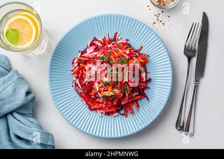 Salade de vitamines avec betteraves, chou, carottes et graines de sésame sur fond gris. Régime alcalin. Vue de dessus. Banque D'Images