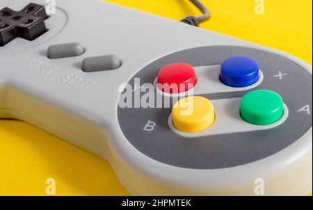 Gros plan de la manette de jeu 8 bits de couleur grise classique sur fond jaune. Banque D'Images