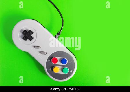 Gros plan de la manette de jeu 8 bits de couleur grise avec fil classique sur fond vert. Banque D'Images