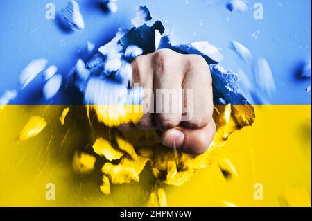 Un poing traverse un mur de béton aux couleurs du drapeau national ukrainien. Le concept d'agression russe contre l'Ukraine Banque D'Images