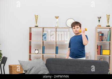 Un jeune garçon s'exerce avec des haltères dans sa chambre. Banque D'Images