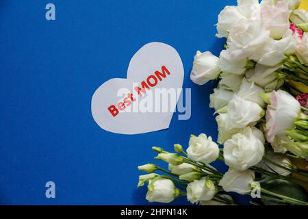 Carte de voeux pour la fête des mères avec fleurs printanières et coeur décoratif sur fond bleu. Composition florale, message d'accueil Card.inscription meilleur maman Banque D'Images