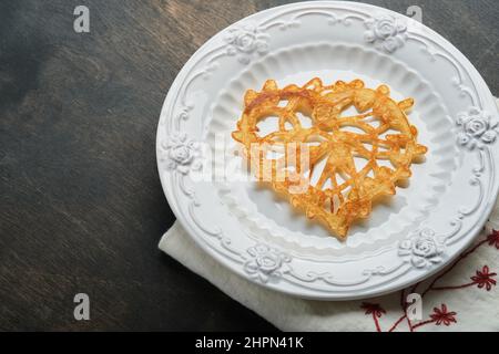 Crêpes ou crêpes en dentelle en forme de coeur sur plaque blanche sur fond rustique ancien.Table pour votre petit déjeuner préféré de la Saint-Valentin.Copie de la vue de dessus Banque D'Images