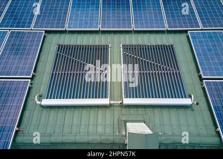 Toiture de bâtiment avec rangées de panneaux photovoltaïques bleus et capteurs solaires d'air sous vide pour le chauffage de l'eau et la production d'électricité écologique propre. Rene Banque D'Images