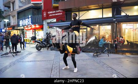 Izmir, Alsancak. Turquie, 21/02/2022, des danseurs de rue qui ont été émigrés en Turquie de la République du Ghana, en Afrique, exécutent leur art de rue dans le quartier le plus populaire d'Izmir, à Alsancak. Un groupe de danseuses africaines, composé de jeunes étudiants, exécute chaque jour leur art à la foule avec un rythme long et élevé. Leur gain financier vient des gens de la rue qui regardent et apprécient leur art. Banque D'Images