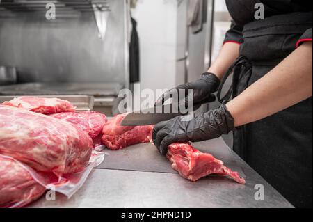 Gros plan de la viande crue et de la boucherie de femme coupant la viande avec un couteau. Photo de haute qualité Banque D'Images