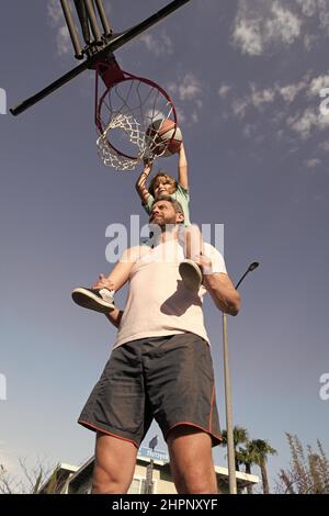 père et fils jouent au basket-ball en plein air. joyeux fête des pères. famille heureuse Banque D'Images