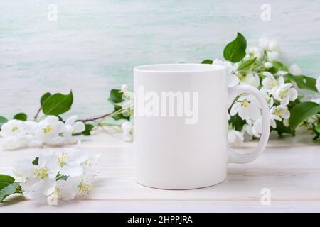 Tasse à café blanc avec fleurs de pommier tendres. Maquette de tasse vide pour promotion du design, modèle stylisé Banque D'Images