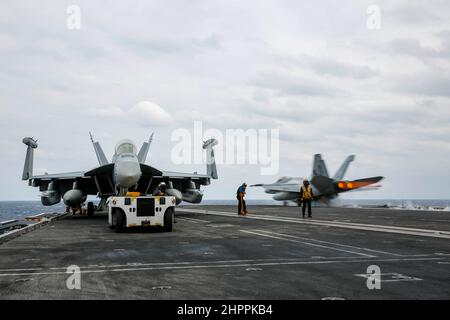 MER DES PHILIPPINES (fév 22, 2022) les marins déplacent un EA-18G Growler, affecté aux « Wizards » de l'escadron d'attaque électronique (VAQ) 133, pendant les opérations de vol sur le pont de vol du porte-avions de la classe Nimitz USS Abraham Lincoln (CVN 72). Abraham Lincoln Strike Group est en cours de déploiement prévu dans la zone d'exploitation de la flotte américaine 7th afin d'améliorer l'interopérabilité par le biais d'alliances et de partenariats tout en servant de force d'intervention prête à l'emploi pour soutenir une région Indo-Pacifique libre et ouverte. (É.-U. Photo de la marine par Michael Singley, spécialiste des communications de masse, classe 3rd) Banque D'Images