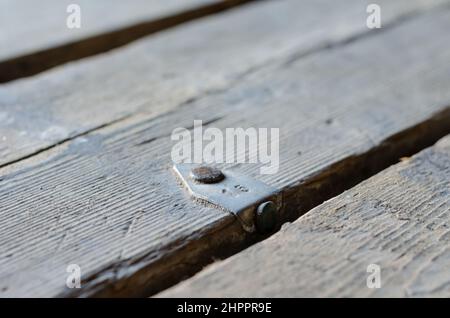 Un cliché défoqué d'un figure15 sur une ancienne planche. Panneau sale avec étiquette en aluminium. Barre métallique clouée au plancher. Gros plan. Flou artistique, bruit, flou, grain e Banque D'Images