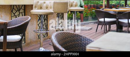 Terrasse du restaurant chaises en bambou en rotin avec coussins blancs et tables en bois carrées sur plancher artificiel Banque D'Images