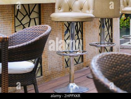 Terrasse du restaurant chaises en bambou en rotin avec coussins blancs et tables en bois carrées sur plancher artificiel Banque D'Images