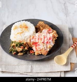 Ayam Goreng Sambal Matah, poulet croustillant avec sauce Chili balinaise, servi avec un œuf dur et une noix de coco épicée Banque D'Images