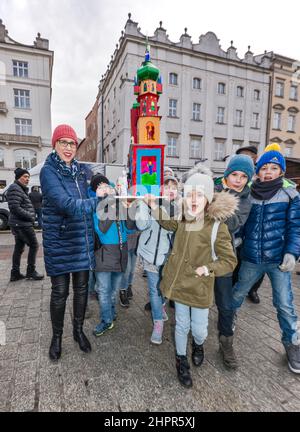 Écoliers, enseignant, portant la scène de la nativité de Cracovie Szopka, faite par eux à l'école, pour exposition lors du concours annuel en décembre, événement inclus dans la liste du patrimoine culturel de l'UNESCO, sur la place du marché principal, Cracovie, Pologne Banque D'Images