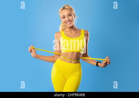 Smiling Young Woman Measuring – ruban de maintien de la taille Banque D'Images