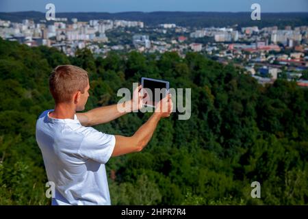 Beau homme prenant des photos panoramiques de la ville sur une tablette. Banque D'Images
