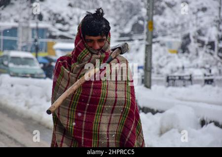 Cachemire, Inde , 23/02/2022, Srinagar, Inde. 23rd févr. 2022. Une main-d'œuvre marche à travers une route enneigée pendant une forte chute de neige à Srinagar.la plupart des régions de la vallée du Cachemire ont reçu mercredi des chutes de neige - la première chute lourde de la saison dans les plaines - perturbant les opérations de vol et de chemin de fer et conduisant à la fermeture de l'autoroute nationale vitale Srinagar-Jammu, les responsables ont dit ici. Crédit : SOPA Images Limited/Alamy Live News Banque D'Images