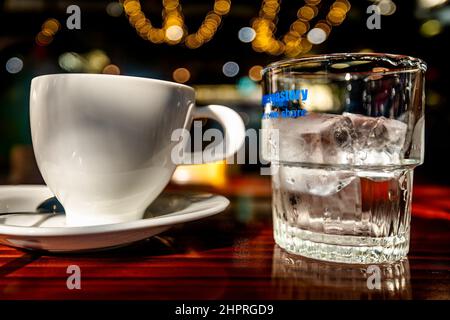 Une tasse blanche et un verre transparent avec de la glace sur une table en bois. Banque D'Images
