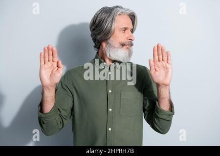 Portrait de l'homme gris sérieux attrayant montrant le rejet de signe d'arrêt regardant de côté isolé sur fond gris pastel couleur Banque D'Images